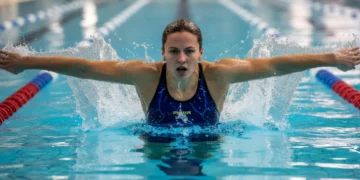 Female swimmer in intense training for Olympic trials, pushing off pool wall